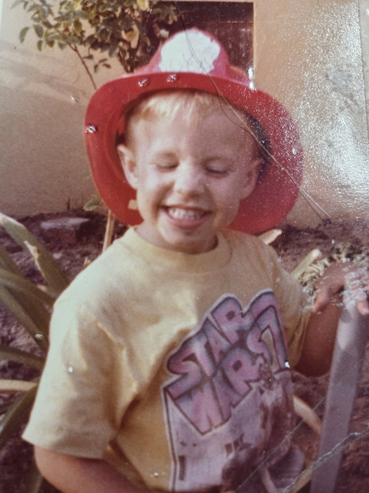 Michael Karl McNeil as a young boy wearing a red toy fire helmet